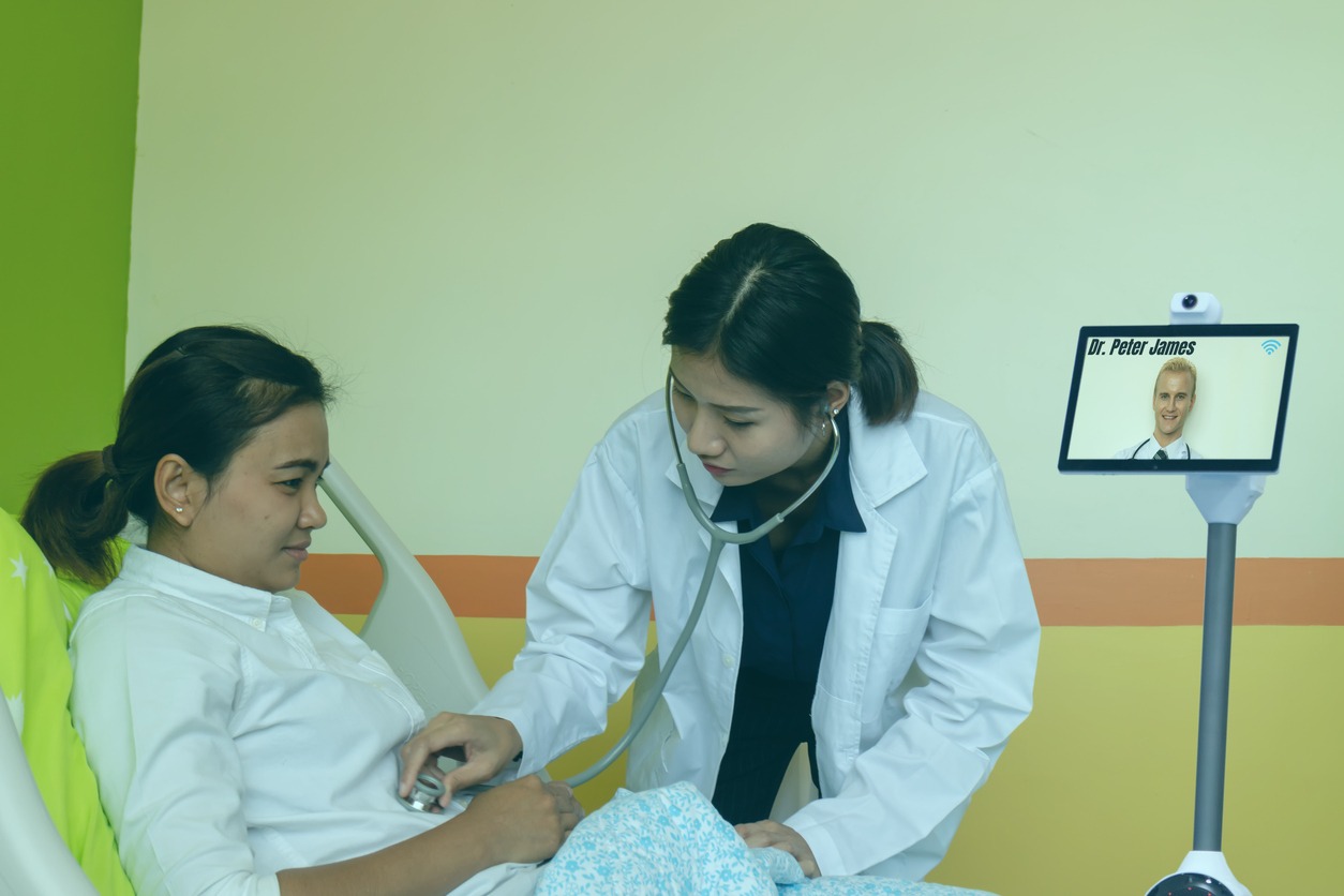 Healthcare professional using a telepresence robotic device to help a patient