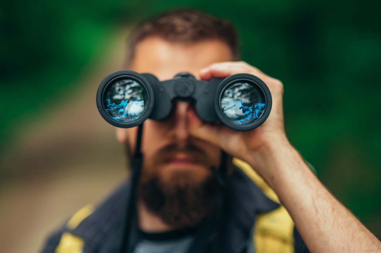 A hiker looking through his binoculars