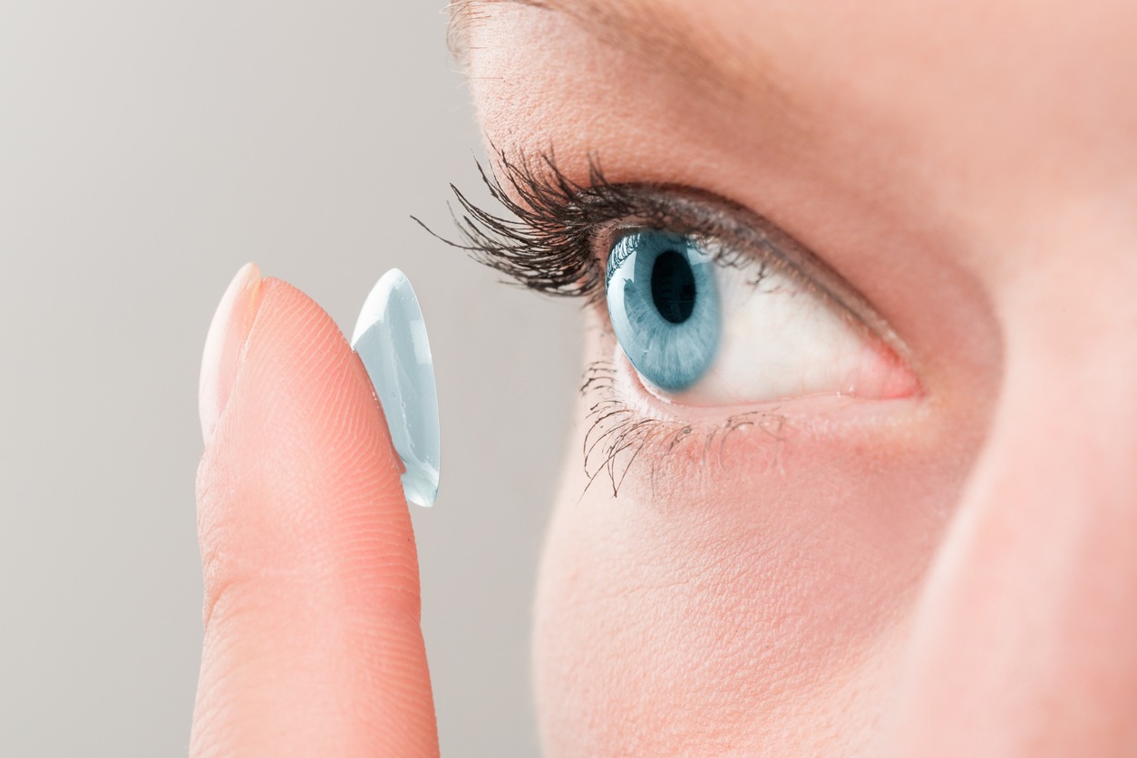 woman inserting a contact lens into her eye