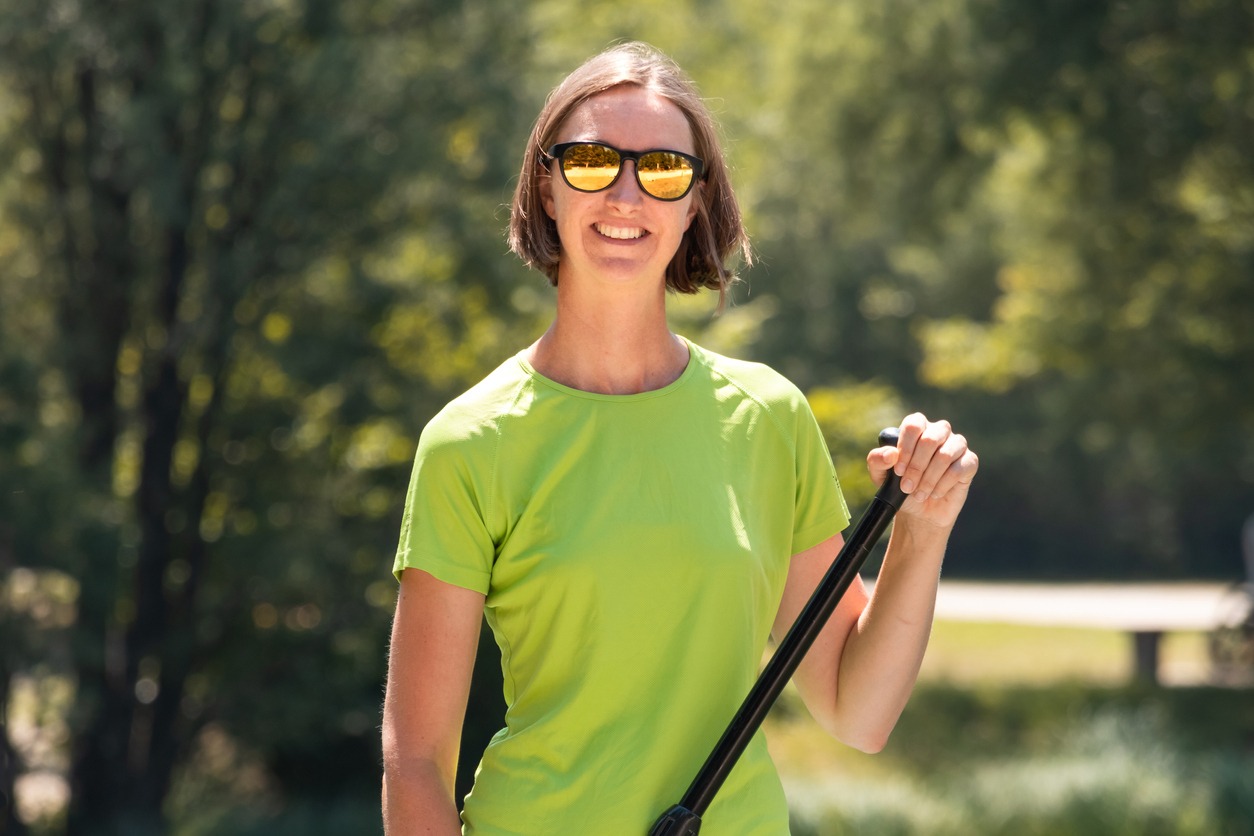 woman stand up paddle boarding with yellow sunglasses