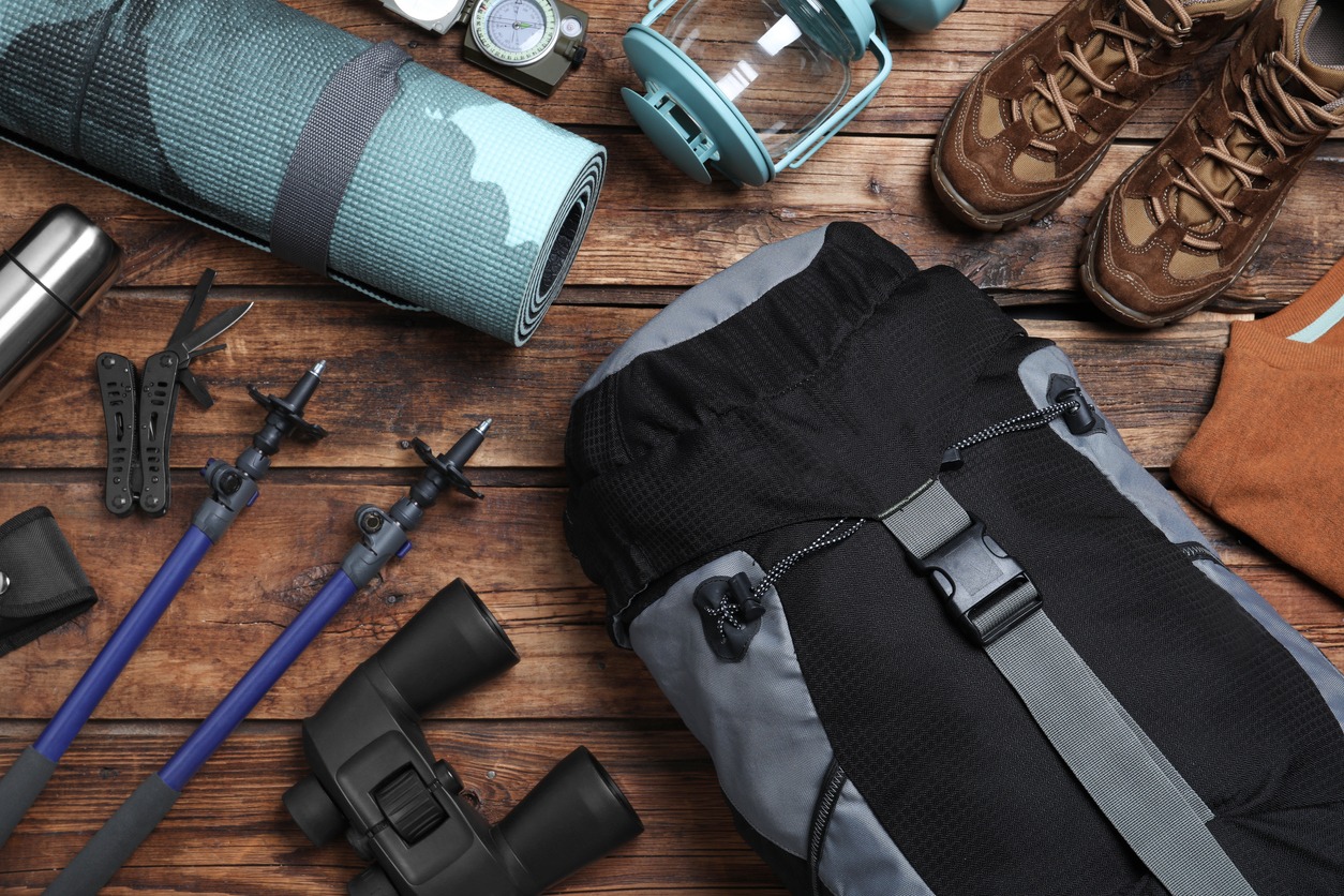 Flat lay composition with backpack and other different camping equipment for tourism on wooden background