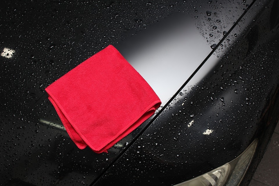 A microfiber cloth wiping down a car’s body.