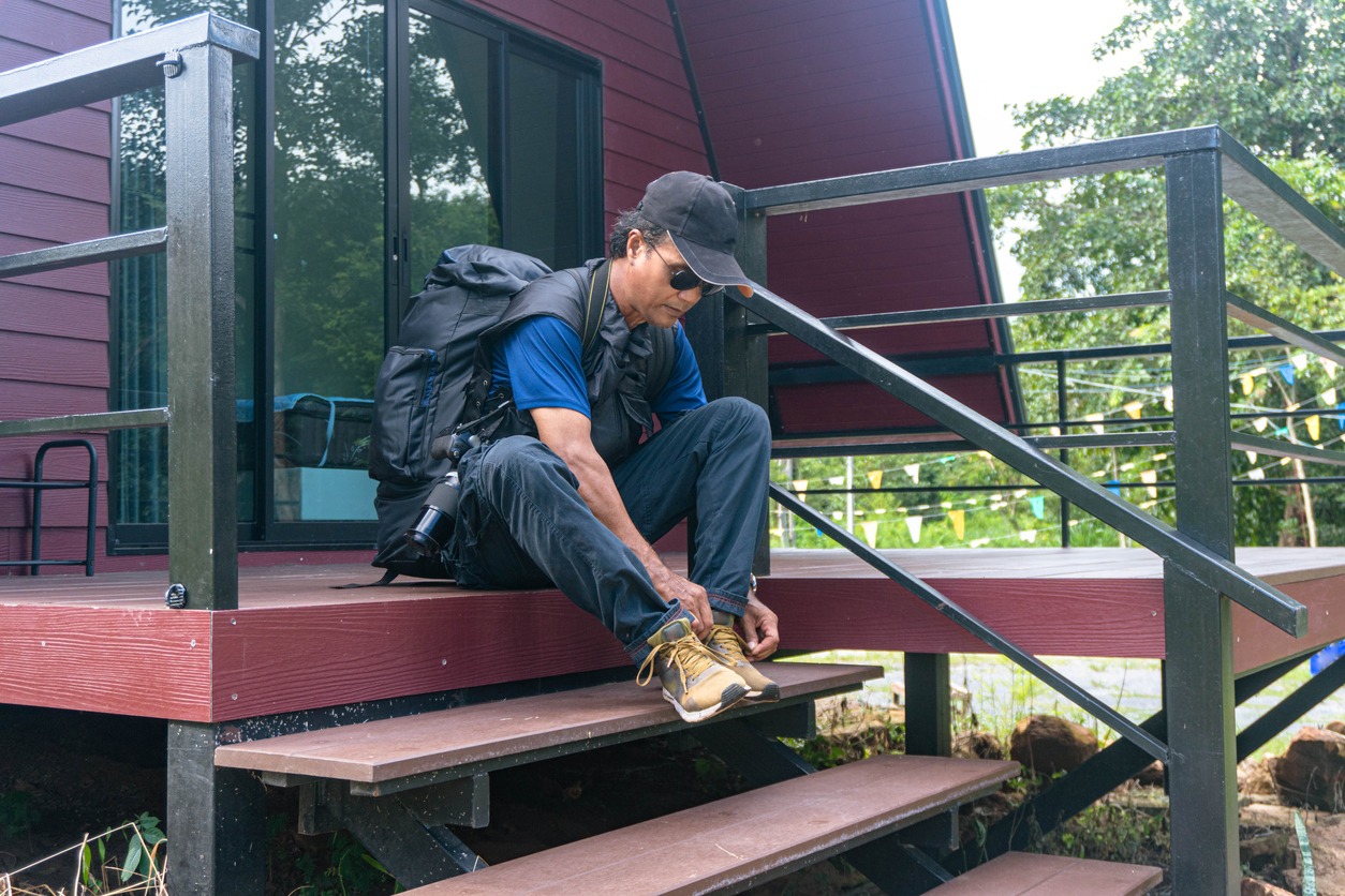 Tourists carrying backpacks capture the beauty of nature sitting on a hillside wooden terrace