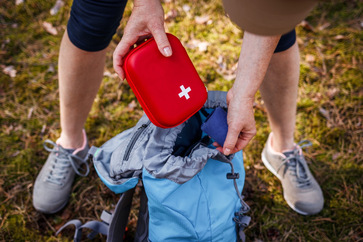 woman placing a first aid kit inside a bag
