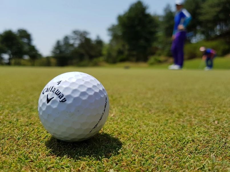 white-golf-ball-two-golfers-wearing-blue-suits-green-grass