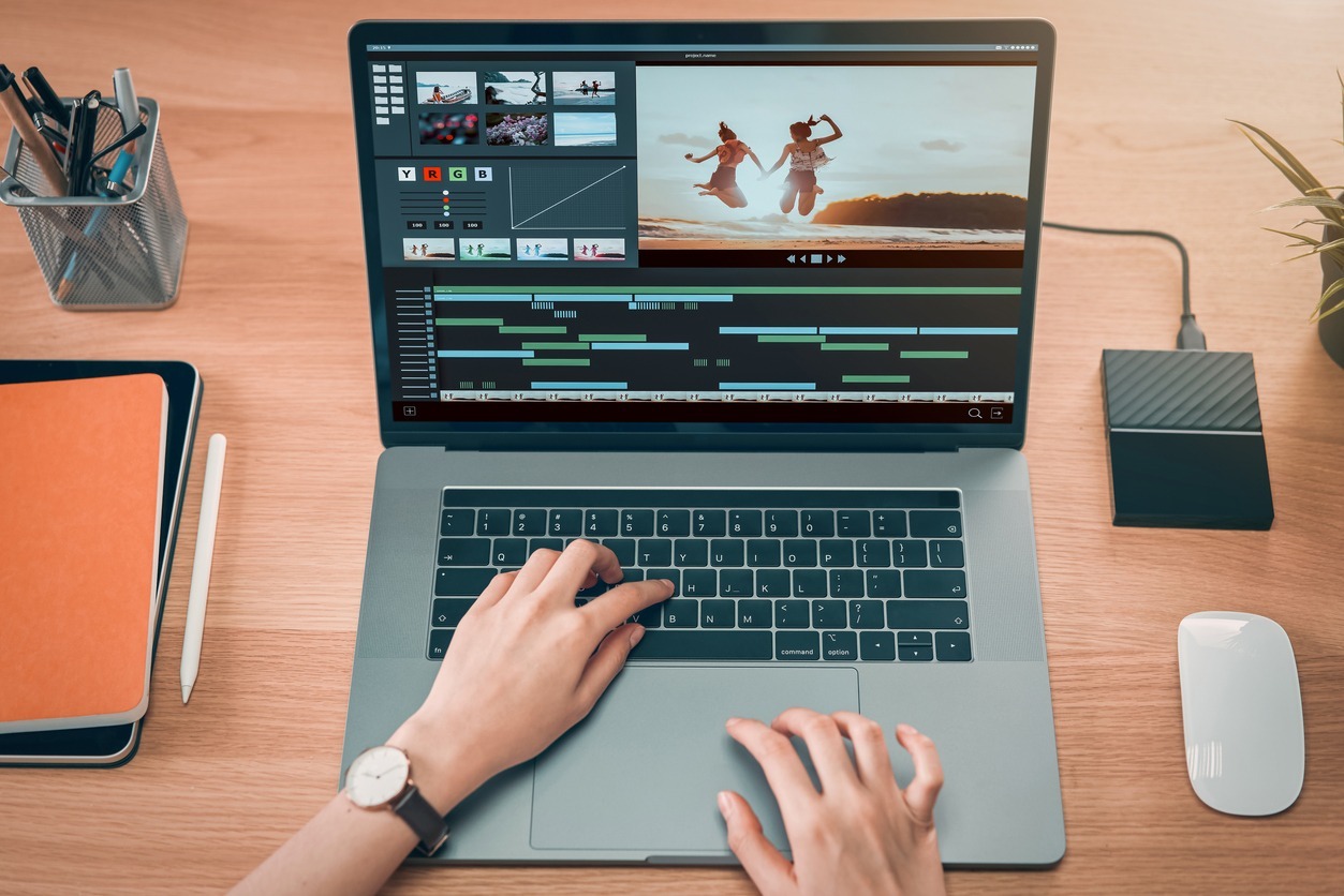 Concept-of-simple-operation-of-blogger-and-vlogger-hand-using-laptop-on-video-editor-works-with-footage-on-wooden-table-camera-and-accessories-on-table