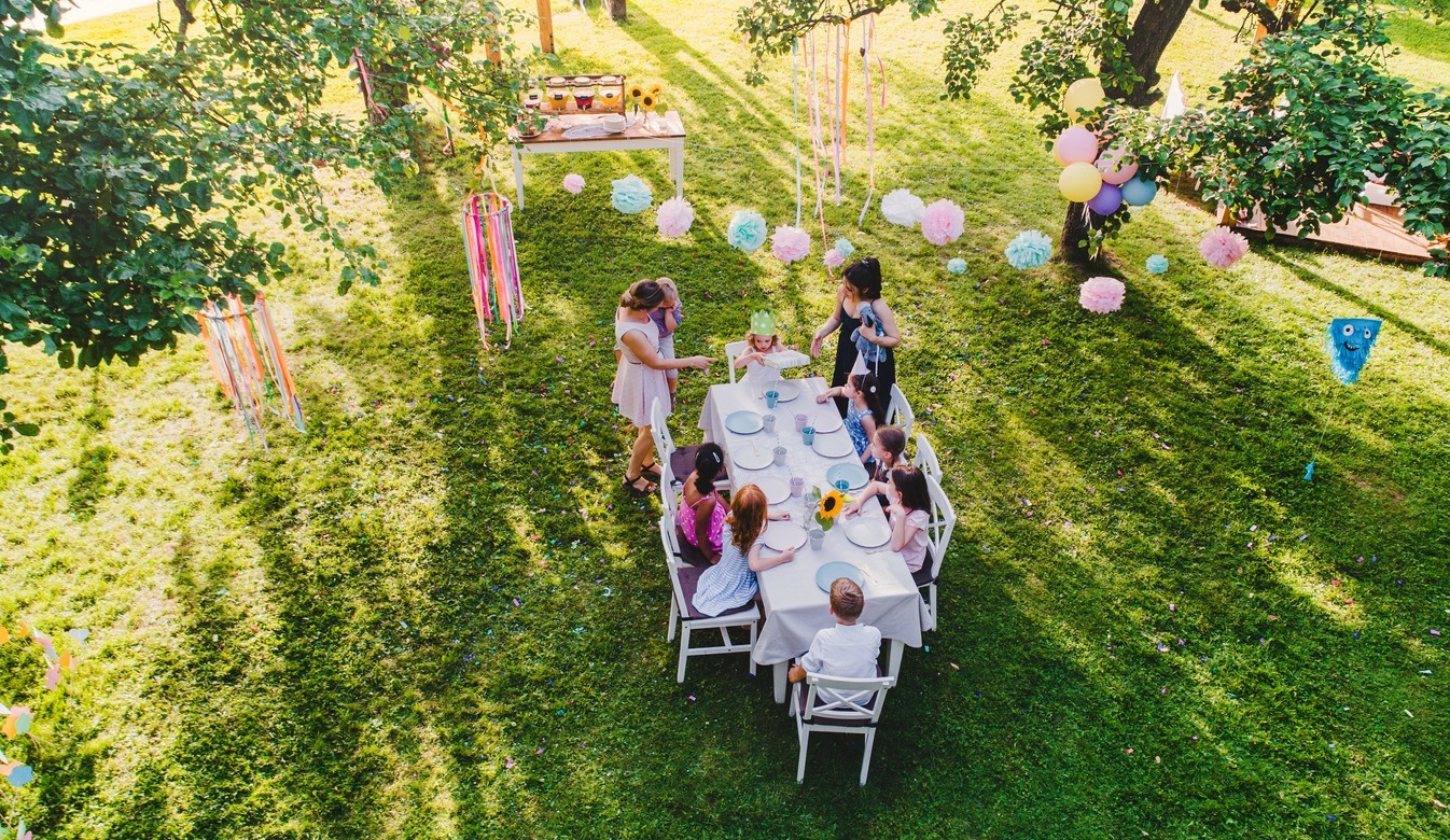 High-angle-view-of-small-children-sitting-at-the-table-outdoors-on-garden-party-in-summer