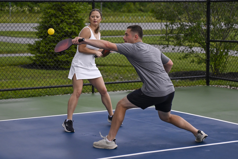 Male pickleball player making a play on the ball observed by his female partner