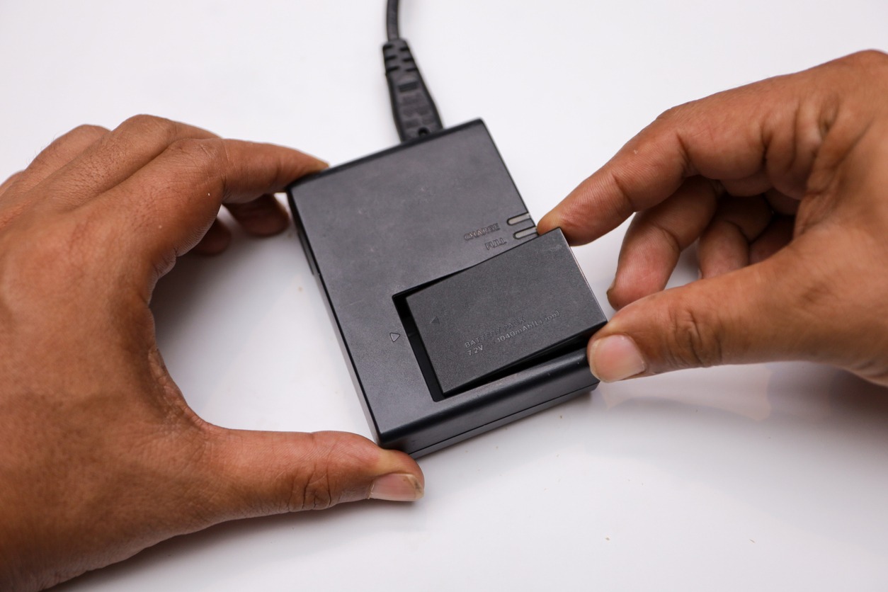 Man charging camera battery using an external charger. 