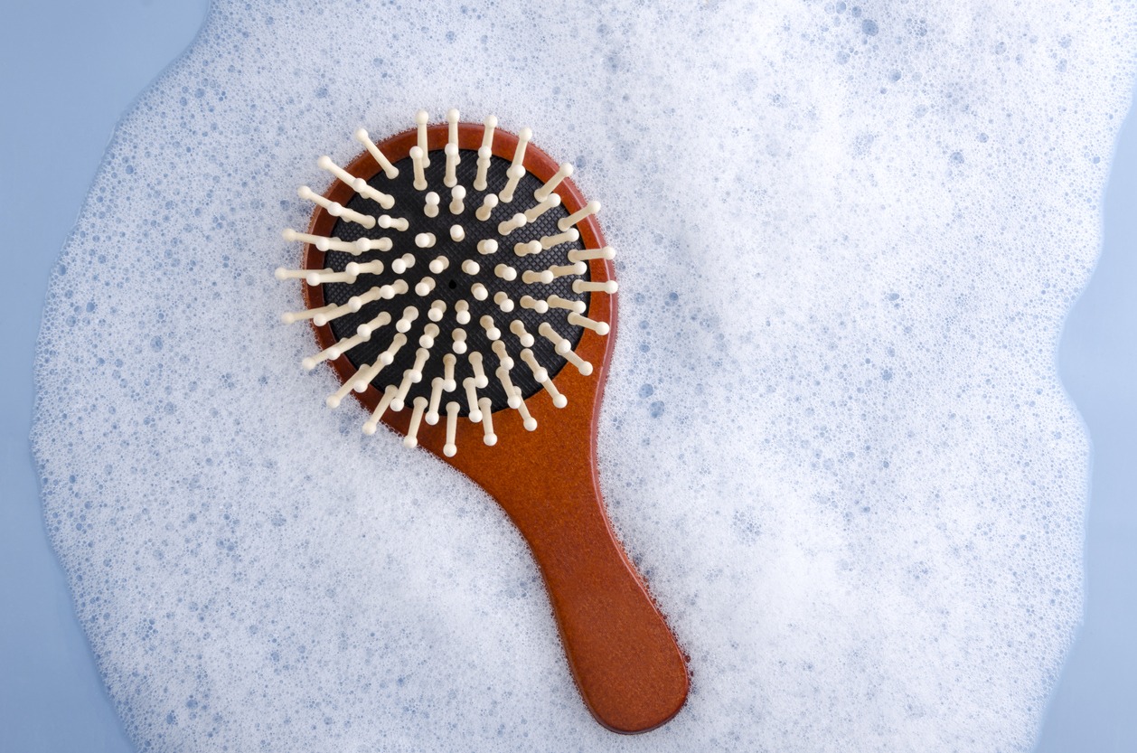 Top view of wooden brush, shampoo