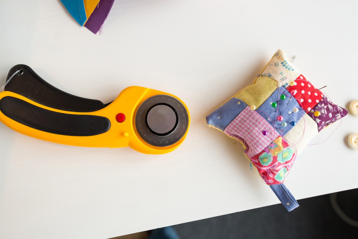 needlework and quilting at the workshop of a tailor on white background - pins, pincushion, buttons, rotary fabric cutters
