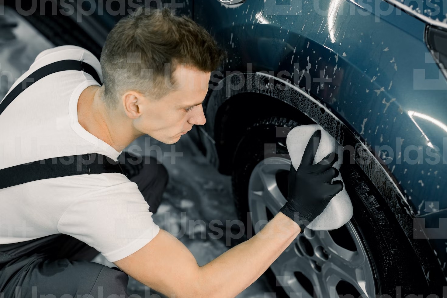 A person cleaning a car’s tire