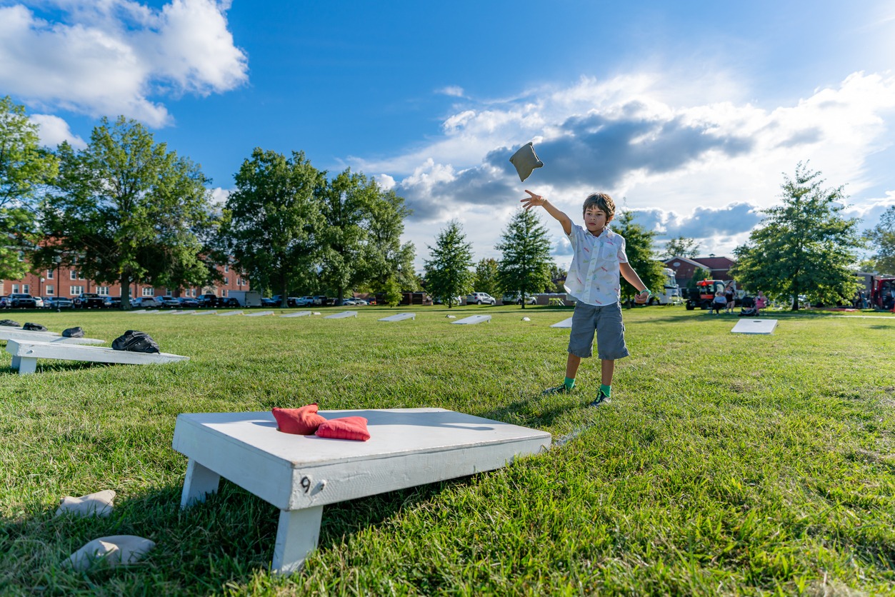  A young boy is tossing bean bags at a corn hole
