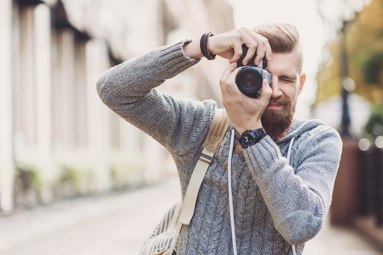 A man taking a picture in the streets using a DSLR camera.