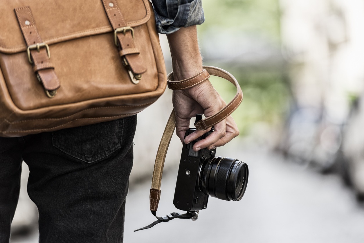 A photographer on the streets with a camera and a leather bag