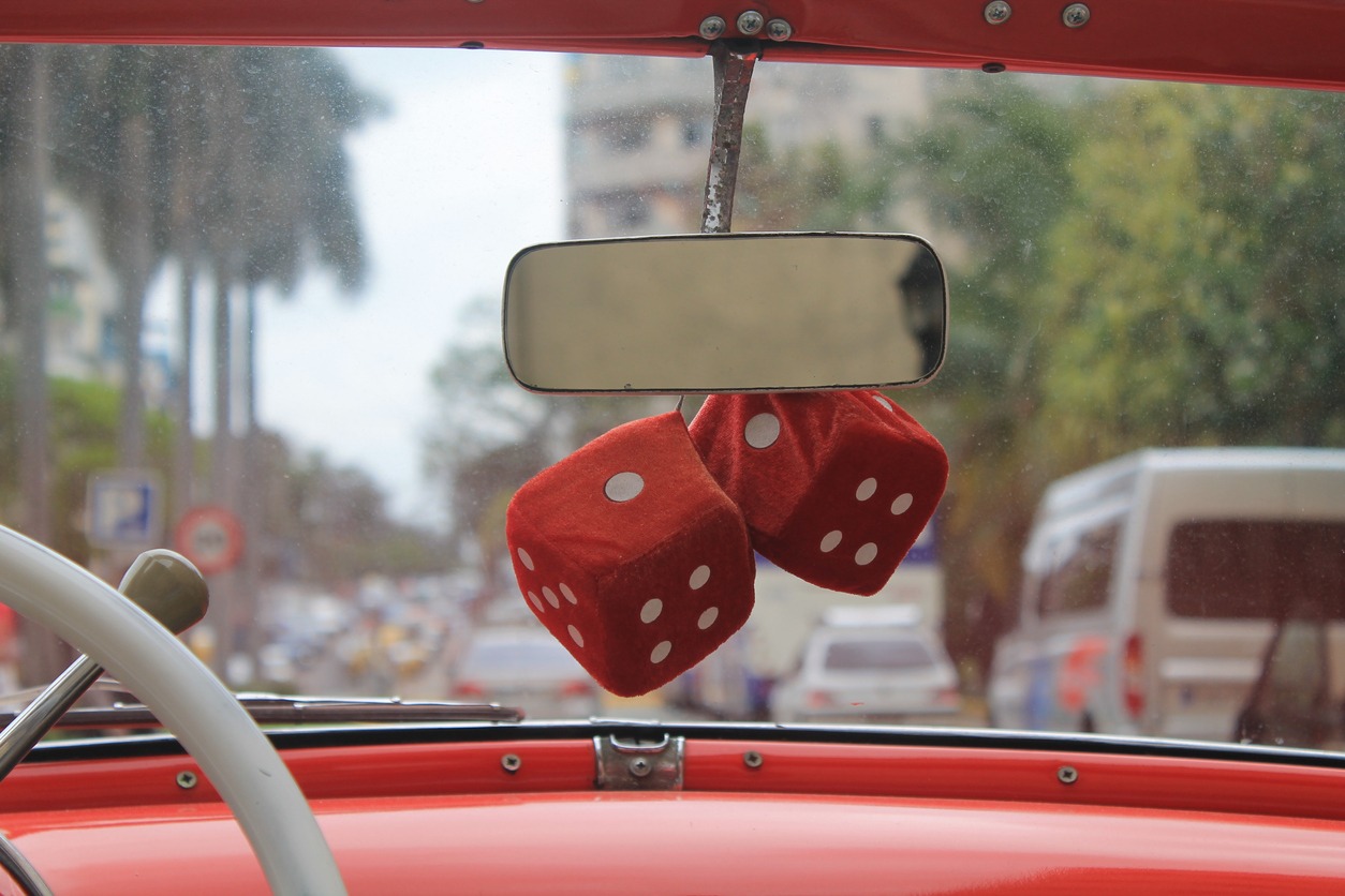 Red fuzzy dice hanging from the car mirror of a red car