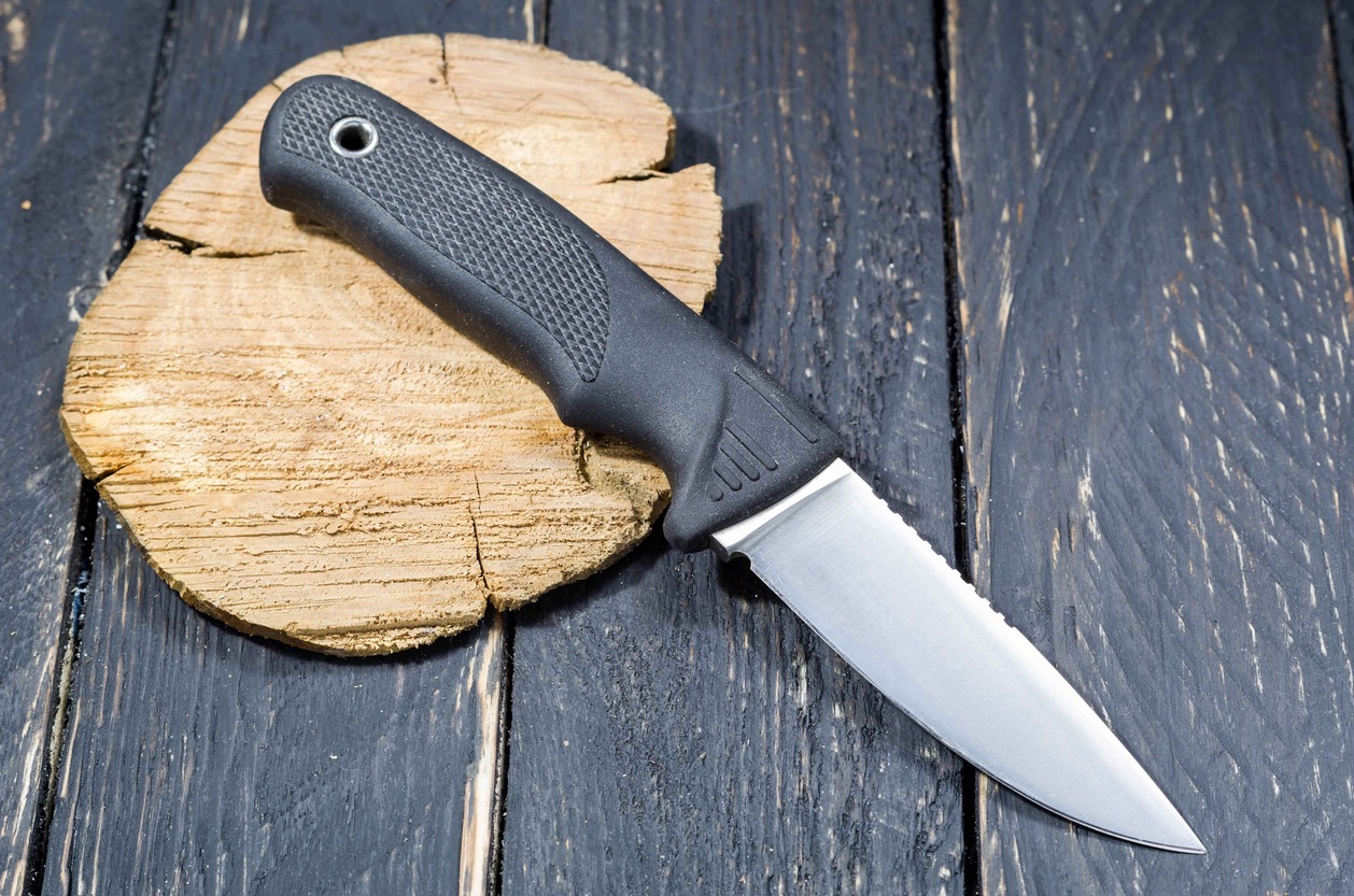 Black handled knife on a wooden surface.
