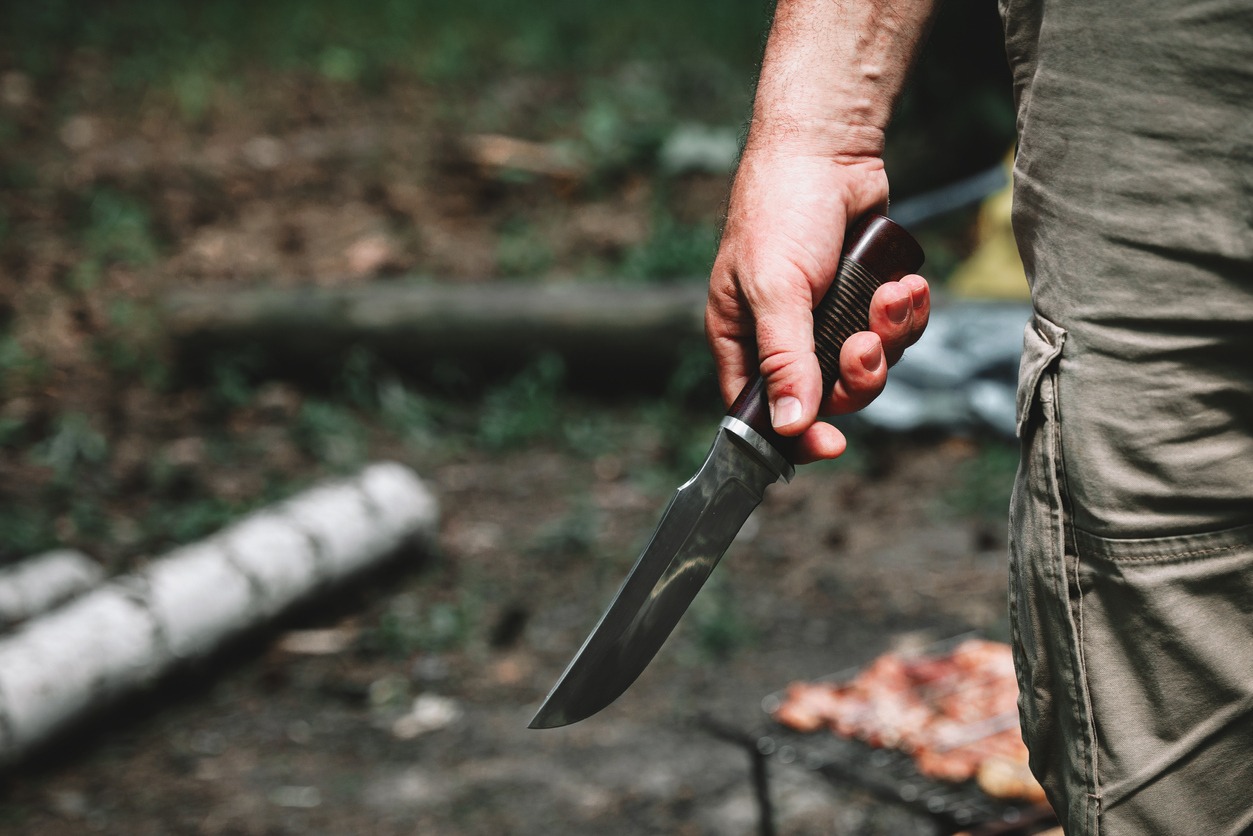 Man holding a hunting knife in the forest.