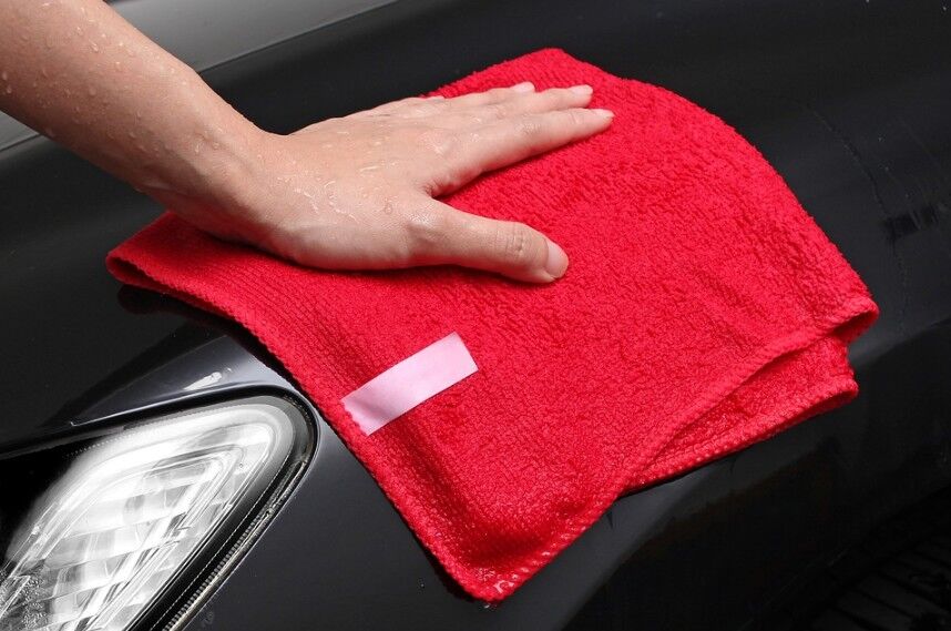 person wiping a car with a microfiber cloth