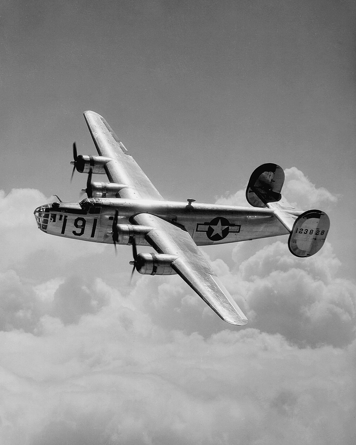 A Consolidated B-24 Liberator from Maxwell Field, Alabama, four engine pilot school, glistens in the sun as it makes a turn at high altitude in the clouds. Heavy Bombers