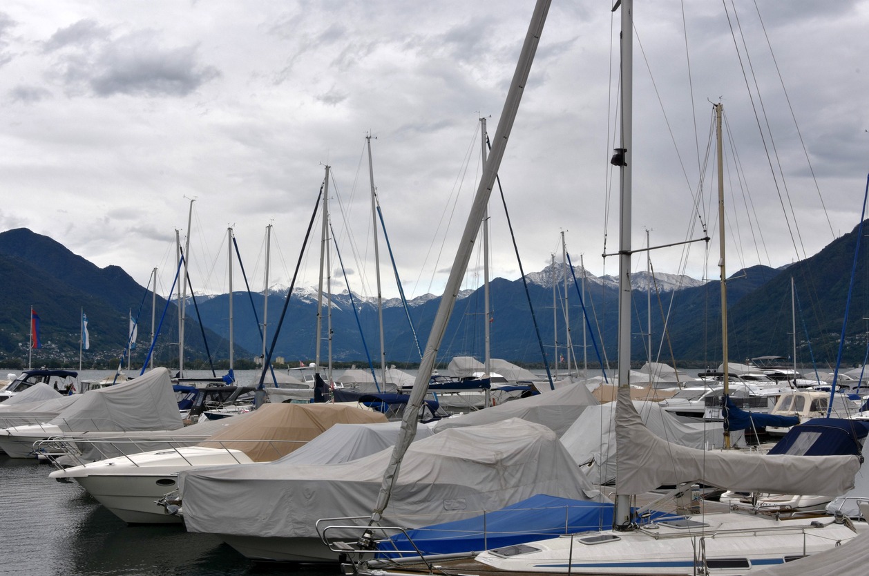 Sailing yachts in a marina covered for winter season and with lowered sails. The vessels anchor on Lake Maggiore in Locarno in Switzerland