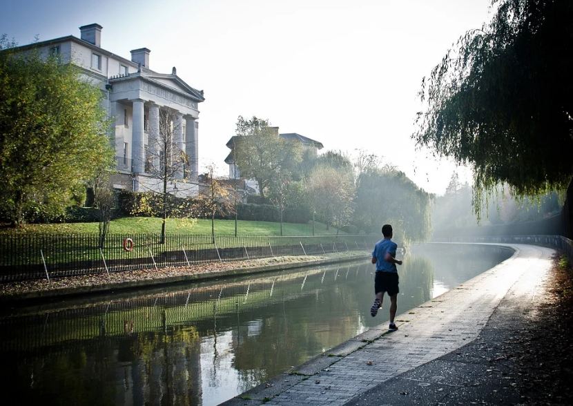 Image of a man running for fitness maintenance near a water canal.
