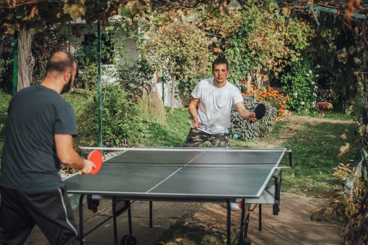 Start up team having fun in the backyard while playing table tennis. Outdoor activity