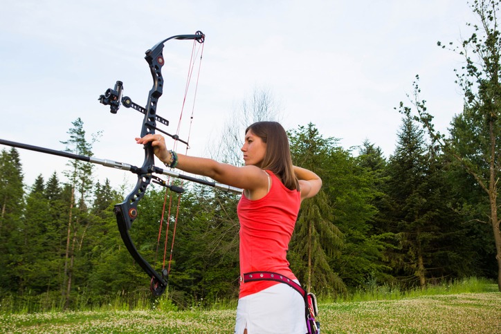 Young woman with bow and arrow aiming at target