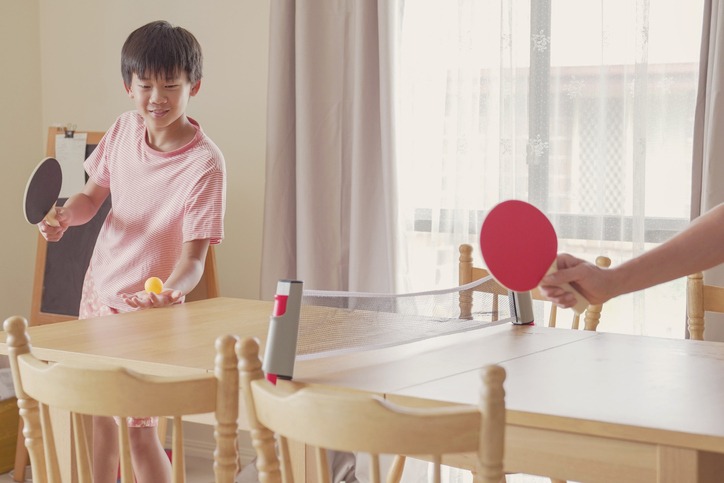Healthy mixed Asian preteen boy playing table tennis on dining table at home, tween exercise, child fitness, stay healthy and fit during social distancing, isolation concept