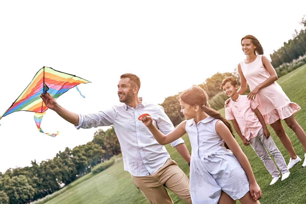 Weekend activities. Family with a kite walking on field in nature smiling cheerful