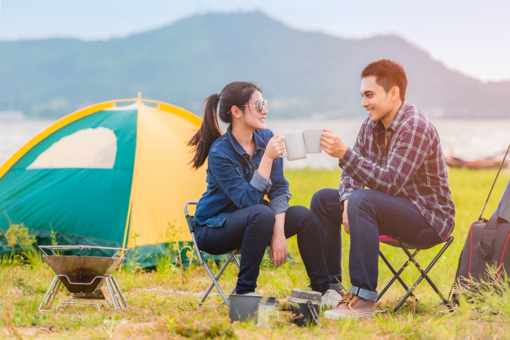 A couple camping and drinking coffee