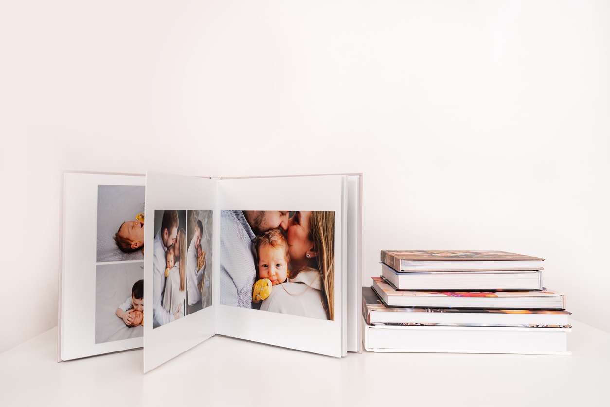A photo book from a family portrait with a new infant is open on a white table
