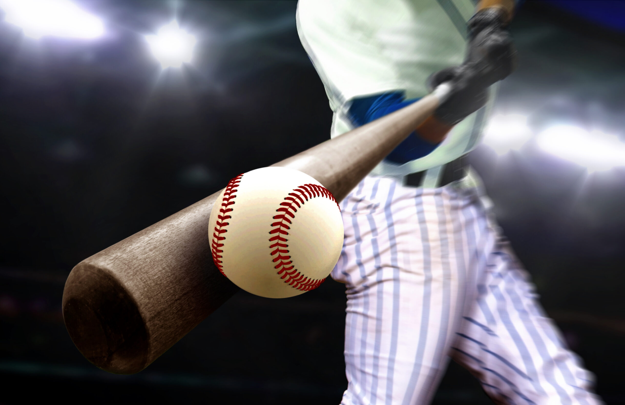Baseball player swing hitting ball with bat in close up under stadium spotlights