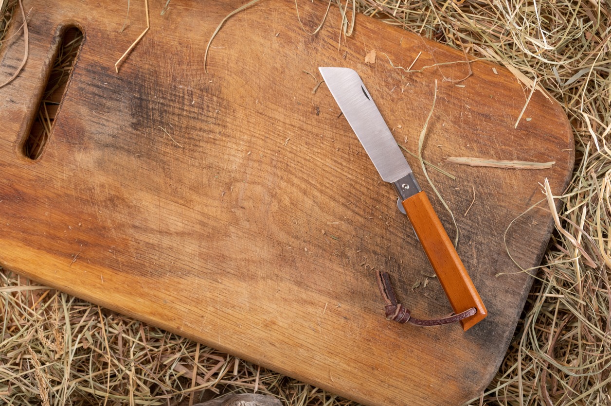 Folding knife with a tanto blade. Portuguese knife with wooden handle. Knife on cutting board. Top view