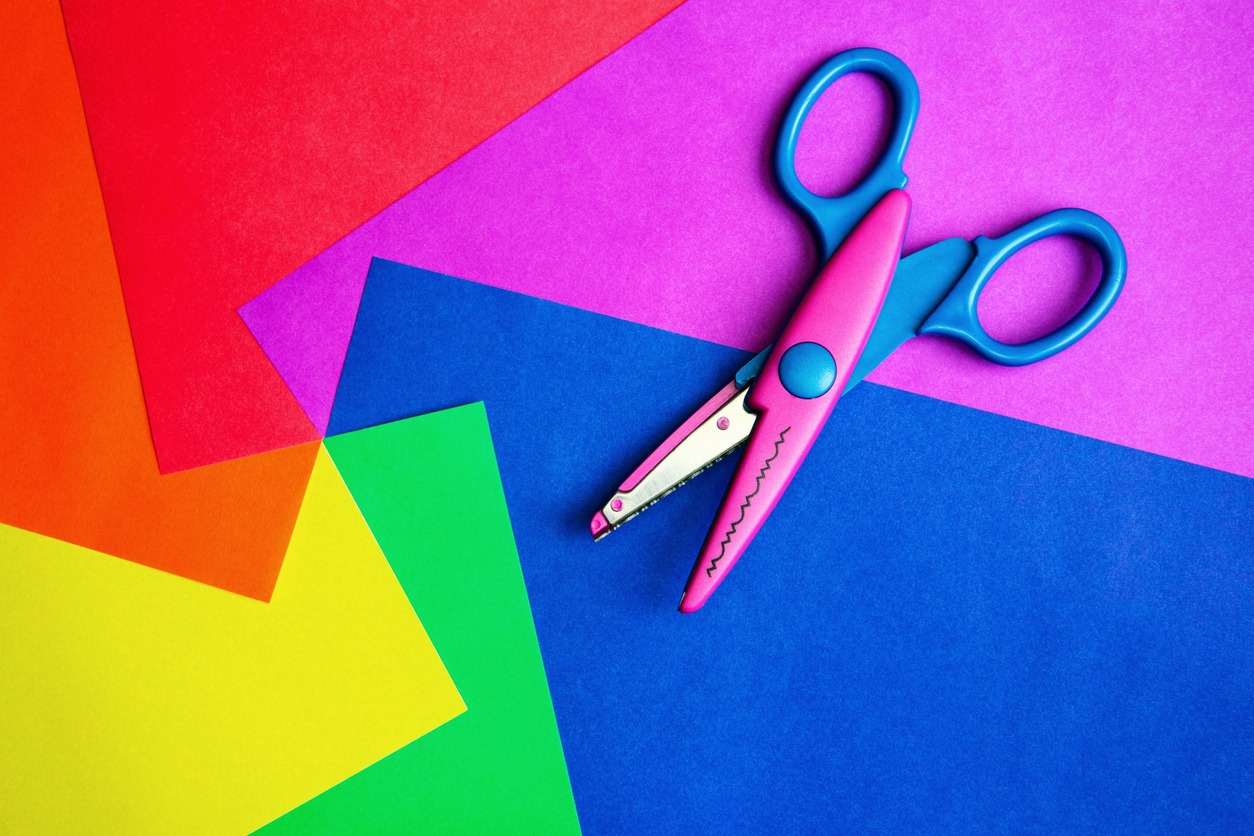 Rainbow-colored pieces of paper are scattered with pattern scissors