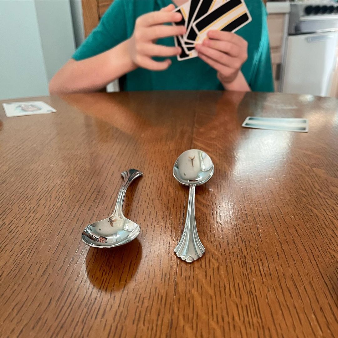 Two people playing Spoons with two spoons on the table