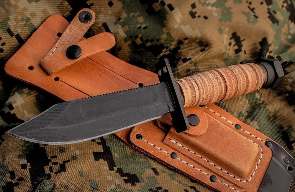 a-survival-knife-having-a-black-blade-and-brown-handle-on-top-of-a-leather-sheath