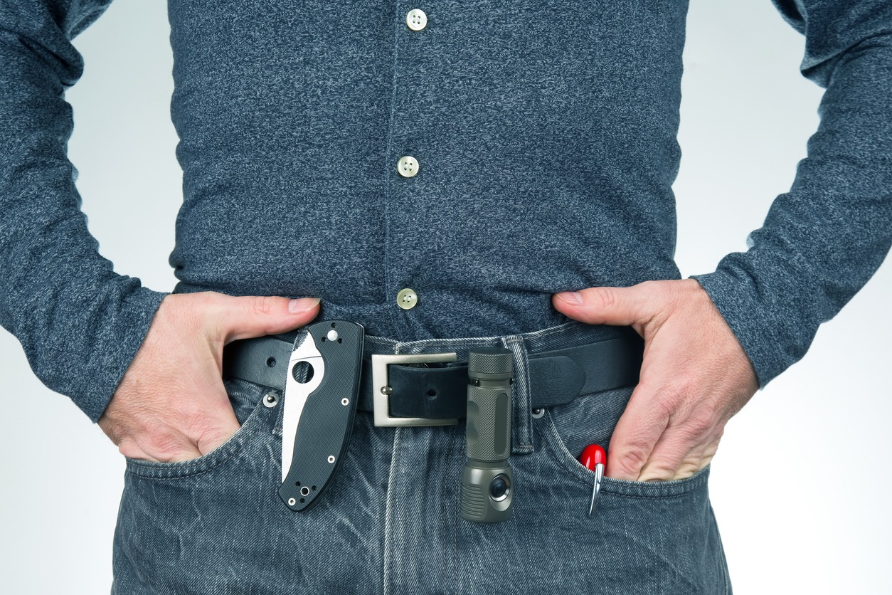 man in jeans on a leather belt with a flashlight and a knife. survival items