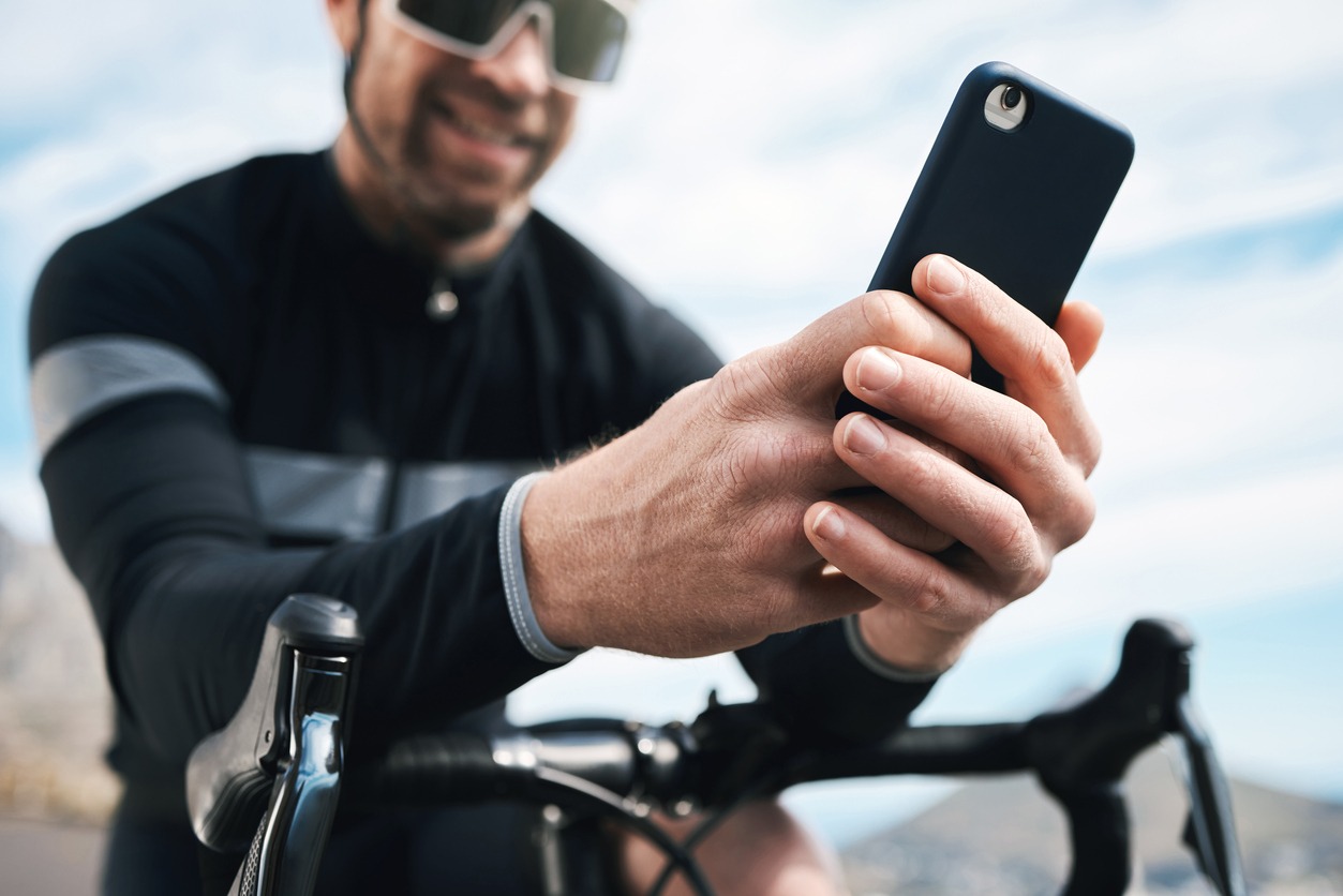 Cropped shot of a handsome mature man sending a text while cycling outdoors