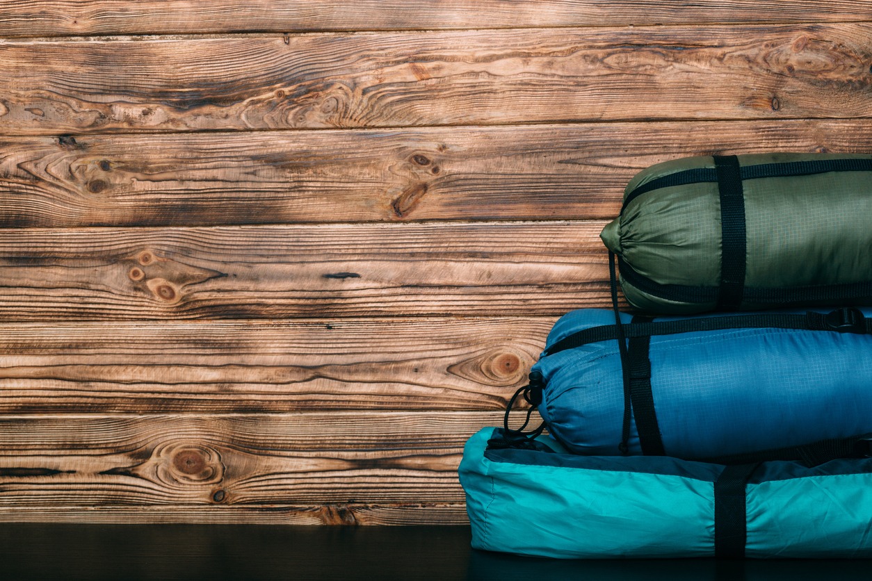 sleeping bags and tent on wooden background
