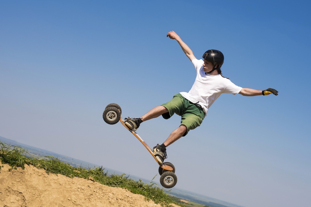 Sporty female jumping with mountainboard over the hill