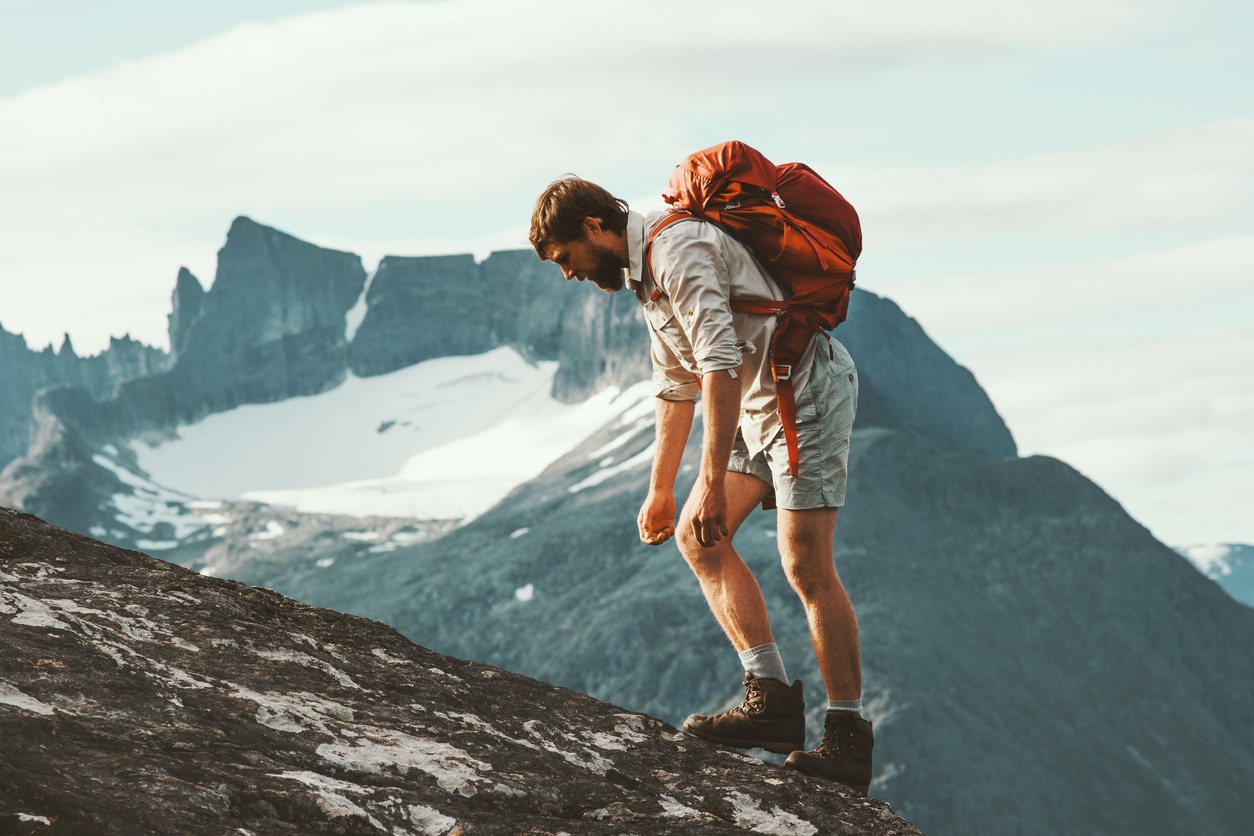 Tired Man in mountains with backpack Norway Travel lifestyle hiking hard trek concept adventure summer vacations