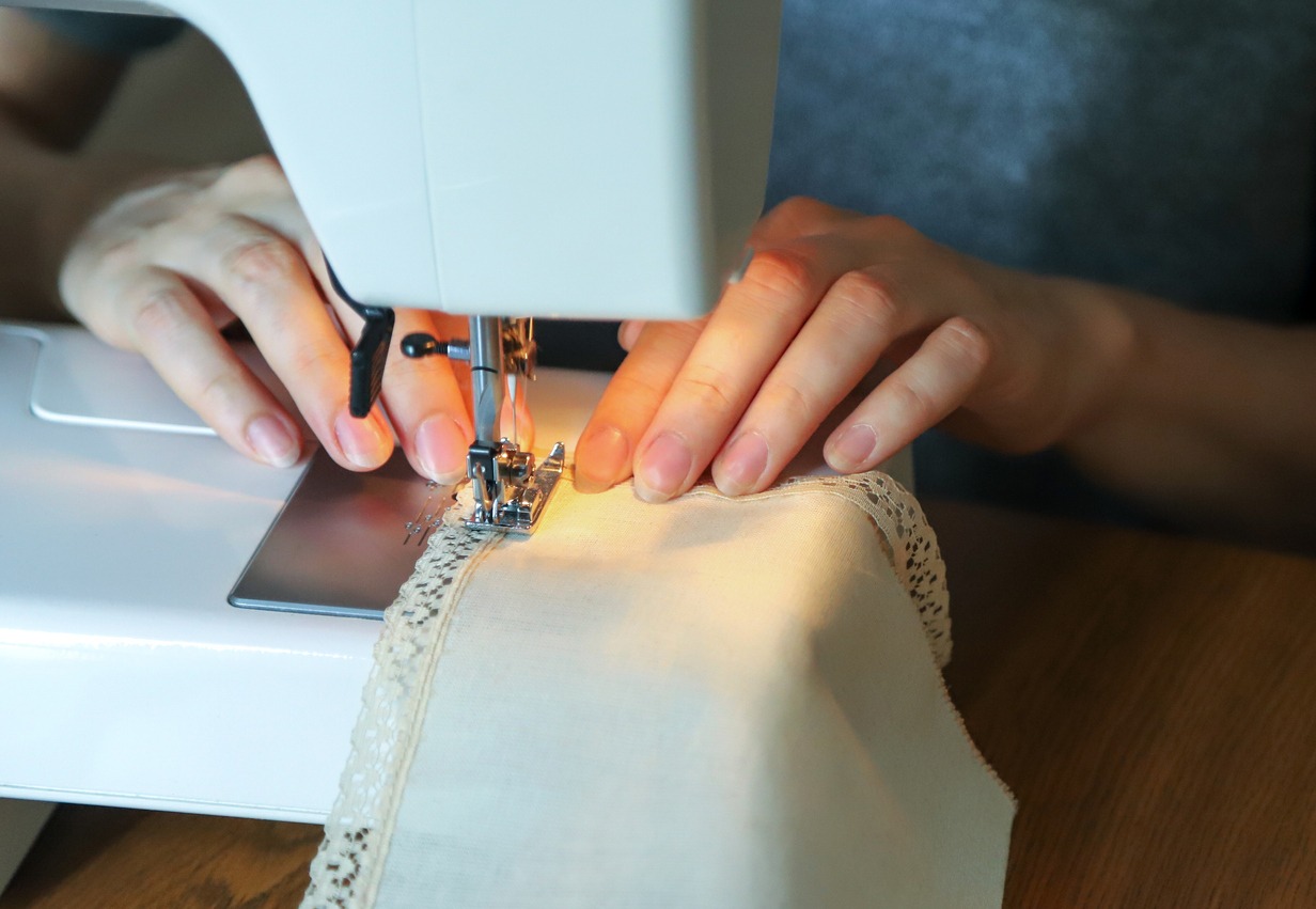 Working process of a tailor. Craftsperson attaches lace to a napkin with a sewing machine
