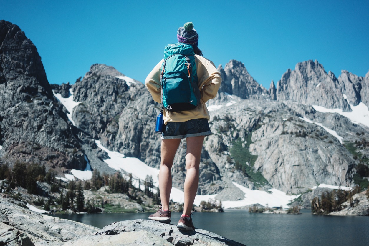 Young woman hipster hiking in wilderness with backpack
