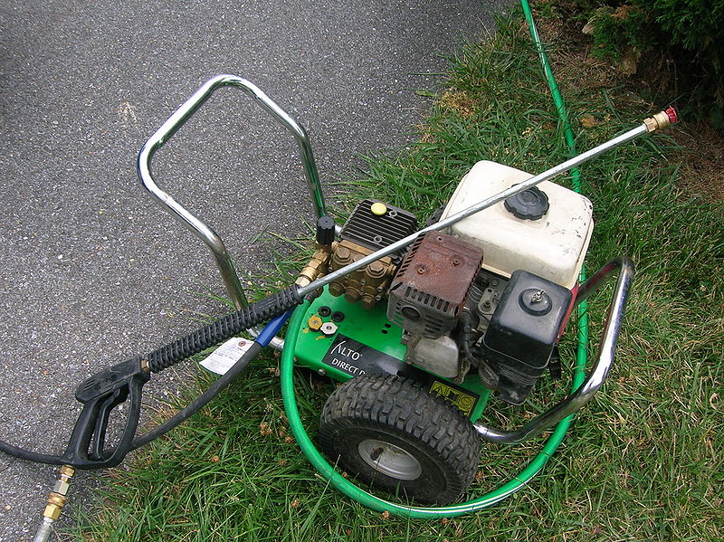 A green gasoline pressure washer on grass