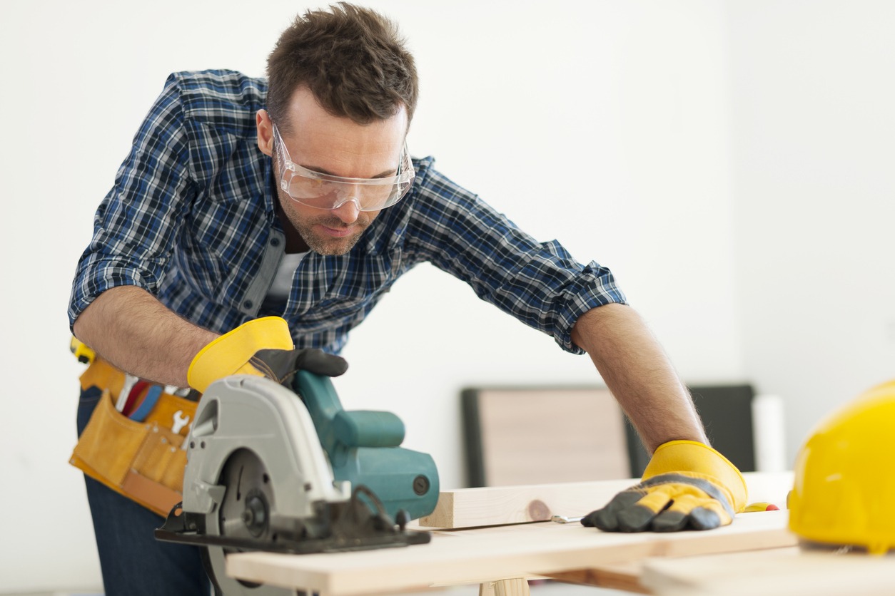 A man using a sanding tool while wearing safety goggles