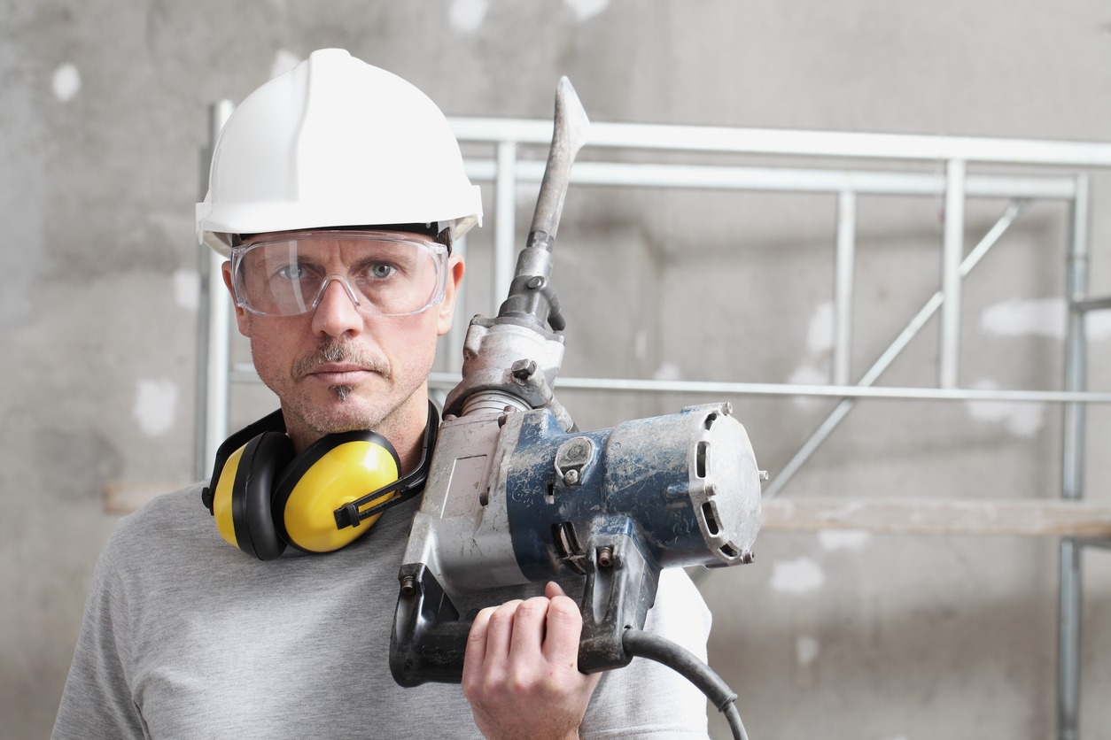 A man wearing safety goggles and other protective gear while holding a jackhammer