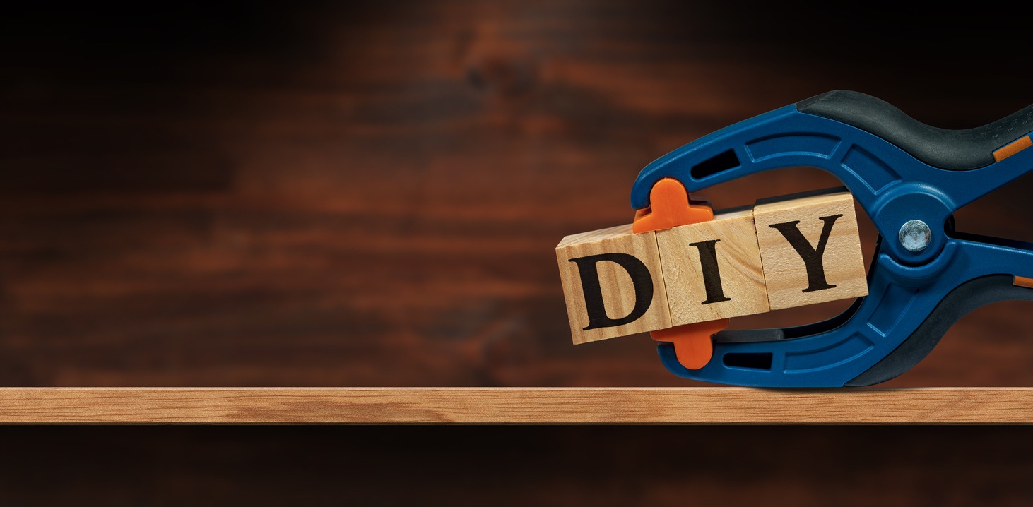 A spring clamp holding wooden letter blocks spelling out “DIY”