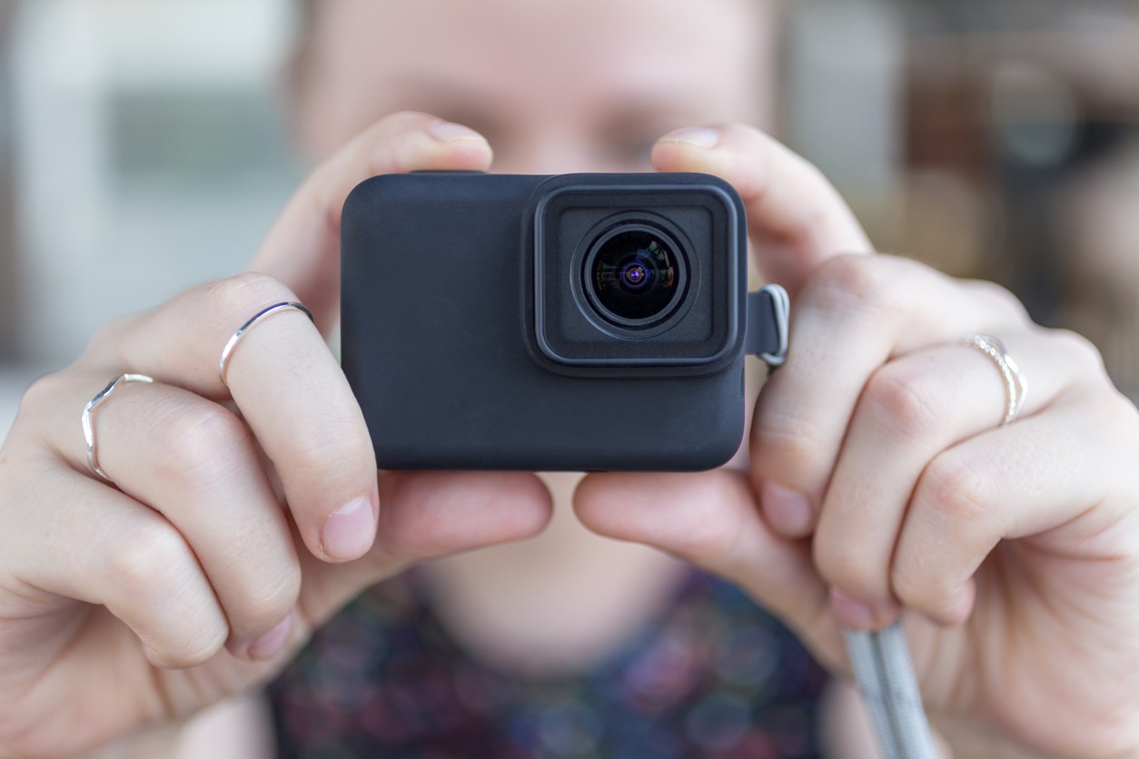 A woman holding a GoPro ready to take a picture.