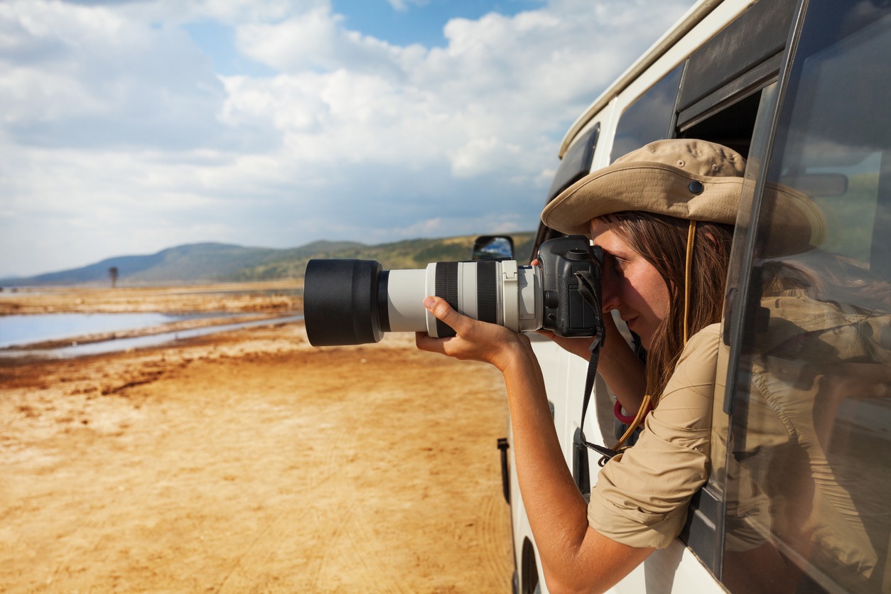 A woman taking a photo of Kenyan lake Nakuru from the open window of safari jeep